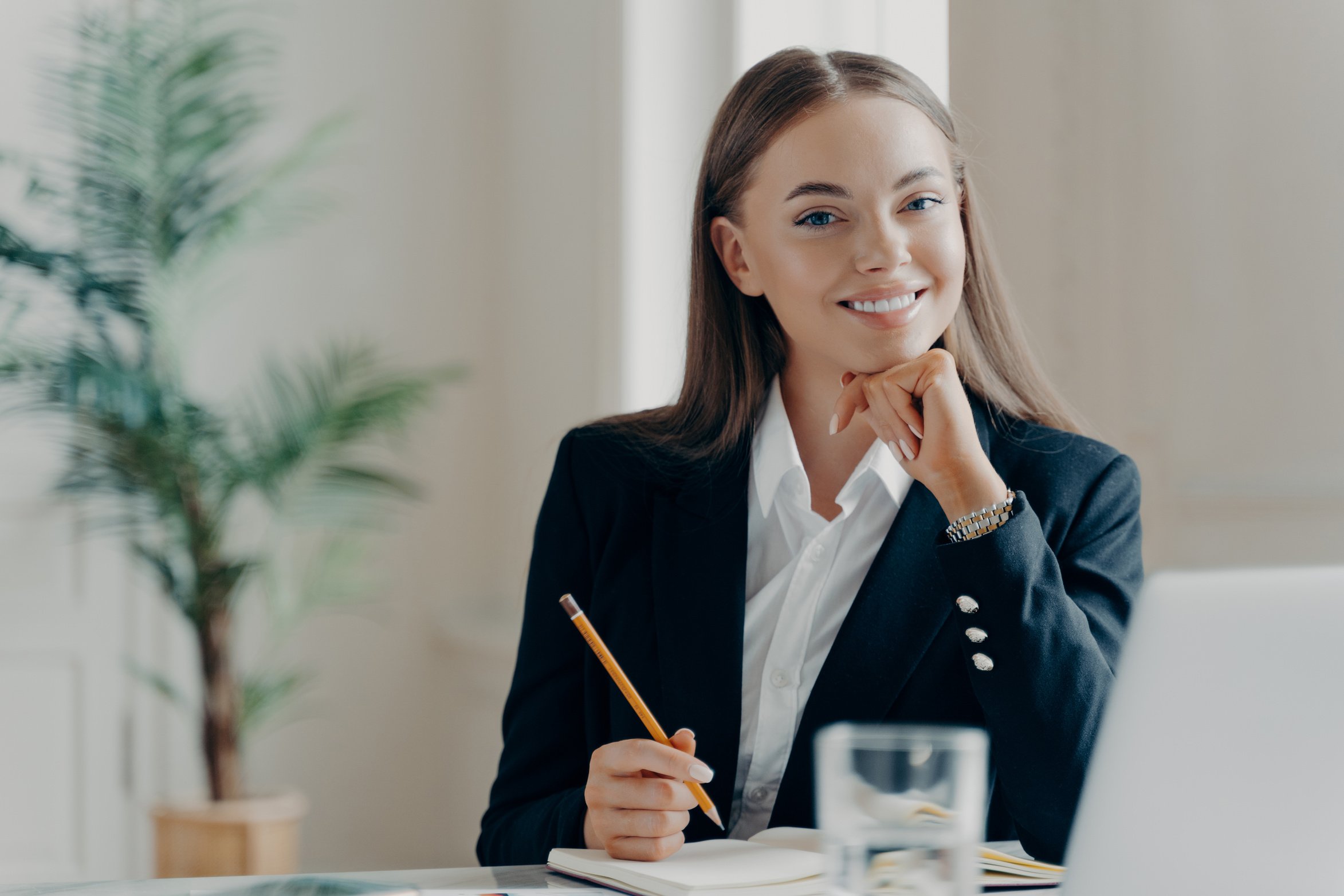 Smiling Bussiness Woman Sitting by Desk Looking at Camera